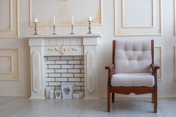 Wooden beige armchair stands next to fireplace. Vintage furniture. Cozy interior