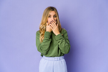 Young caucasian blonde woman covering mouth with hands looking worried.