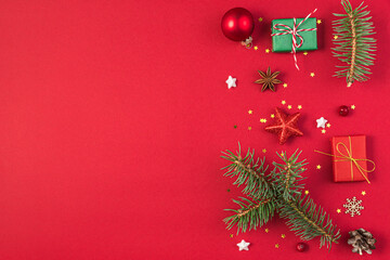 Christmas composition on red background made of gifts, fir tree, decorations. Flat lay, top view