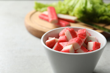 Cut crab sticks in bowl on light table, closeup. Space for text