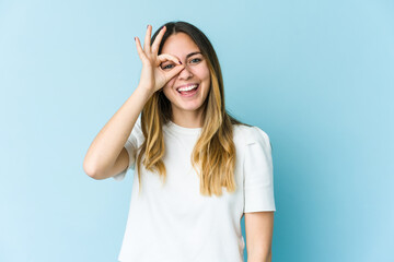 Young caucasian woman isolated on blue background excited keeping ok gesture on eye.