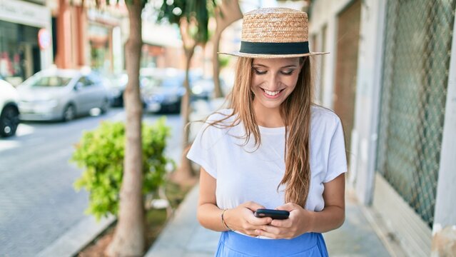 Young blonde woman on vacation smiling happy using smartphone at street of city