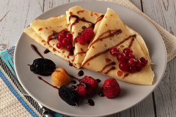 Pancakes with raspberries, currants and chocolate, decorated with a mint leaf