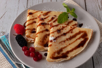 Pancakes with raspberries, currants and chocolate, decorated with a mint leaf
