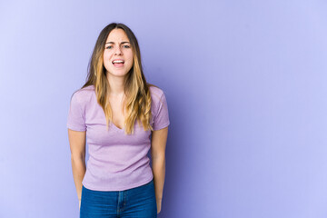 Young caucasian woman isolated on purple background shouting very angry, rage concept, frustrated.