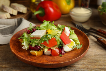 Delicious salad with crab sticks and lettuce on wooden table