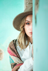 A beautiful blonde-haired girl with a hat between the walls