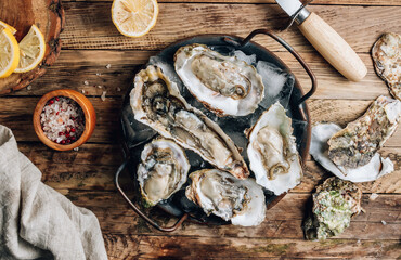 Fresh oysters with ice and lemon on a rustic wooden background.