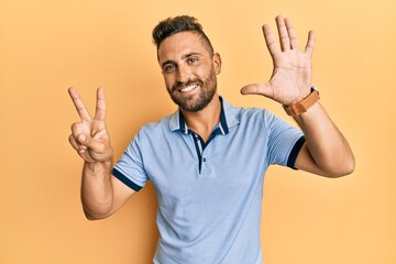 Handsome man with beard wearing casual clothes showing and pointing up with fingers number seven while smiling confident and happy.