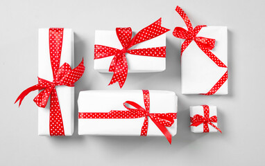 Christmas gift boxes with red bows on grey background, flat lay
