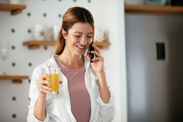 Young woman in kitchen. Beautiful woman preparing breakfast and using the phone.