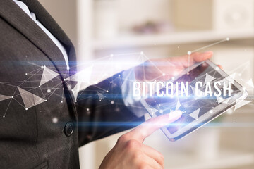 Close up hands using tablet with BITCOIN CASH inscription, modern business technology concept