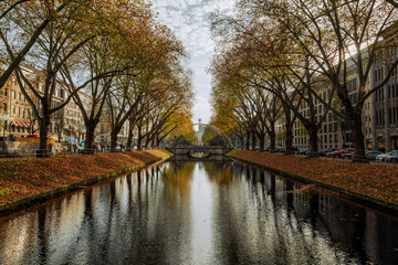 Fototapeta na wymiar Outdoor and Diminishing perspective view over the canal between shopping street, pedestrian walkway and row of tree during autumn season with atmosphere of color changing leaves at Königsalle.