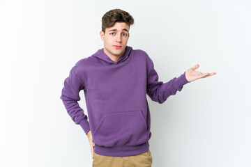 Young caucasian man isolated on white background doubting and shrugging shoulders in questioning gesture.