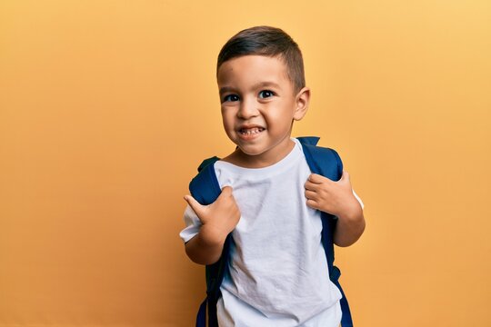 Adorable latin toddler smiling happy wearing student backpack over isolated yellow background.