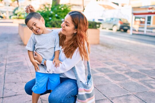 Adorable latin mother and son smiling happy hugging at the city.