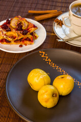 Still life - a hot cup of black coffee, homemade cookies with fruit, baked apples on a bamboo mat