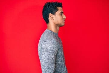 Fototapeta na wymiar Young handsome hispanic man over red background looking to side, relax profile pose with natural face with confident smile.