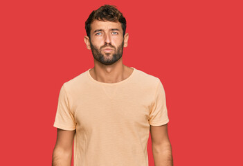 Fototapeta premium Handsome young man with beard wearing casual tshirt looking at the camera blowing a kiss on air being lovely and sexy. love expression.