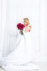 Fototapeta premium Chic blonde woman in luxury white with red bedroom. Rich expensive interior.