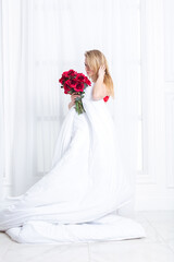 Fototapeta premium Chic blonde woman in luxury white with red bedroom. Rich expensive interior.