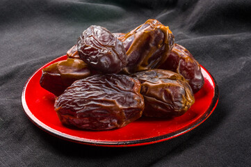 Big luxury dried date fruit in bowls on the dark surface, kurma ramadan kareem concept, close up.