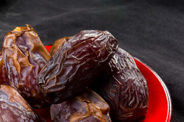 Big luxury dried date fruit in bowls on the dark surface, kurma ramadan kareem concept, close up.