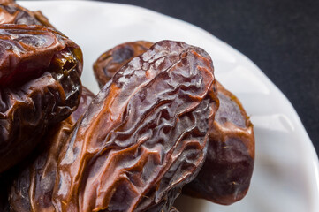 Big luxury dried date fruit in bowls on the dark surface, kurma ramadan kareem concept, close up.