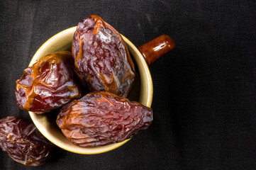 Big luxury dried date fruit in bowls on the dark surface, kurma ramadan kareem concept, close up.