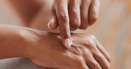 Close up of black woman applying hand cream, making daily beauty treatment at home, slow motion
