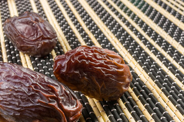 Big luxury dried date fruit on the bamboo mat, kurma ramadan kareem concept, close up.