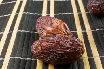 Big luxury dried date fruit on the bamboo mat, kurma ramadan kareem concept, close up.