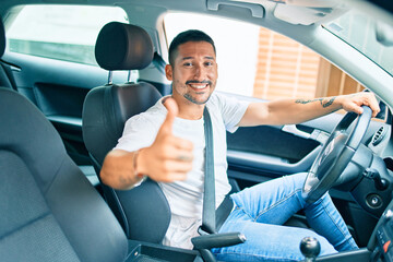 Young hispanic man smiling happy doing ok sign driving car.