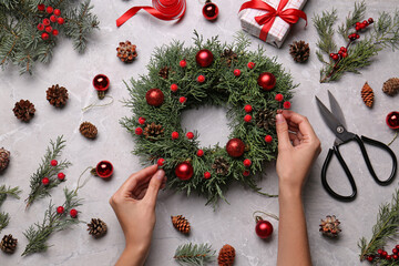 Florist making beautiful Christmas wreath at grey table, top view © New Africa