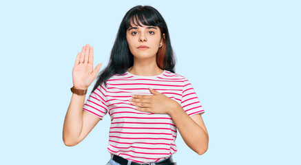 Young hispanic girl wearing casual clothes swearing with hand on chest and open palm, making a loyalty promise oath