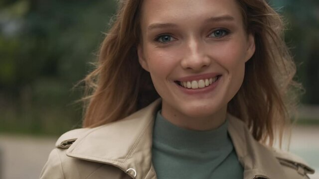 Close up shot of beautiful girl smiling on camera posing outdoor. Female student looking happy walking in park