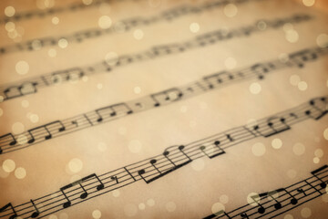 Old sheet with Christmas music notes as background, bokeh effect
