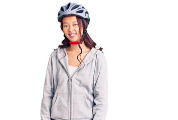 Young beautiful chinese girl wearing bike helmet looking positive and happy standing and smiling with a confident smile showing teeth