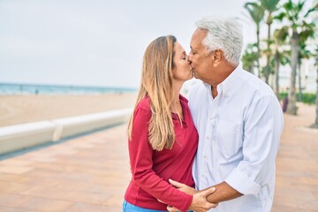 Obraz premium Middle age hispanic couple kissing and hugging walking at street.