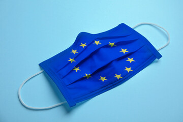 Medical protective mask with European Union flag on light blue background. Coronavirus outbreak in Europe