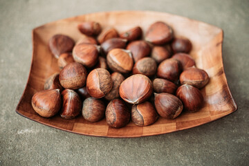 Close up of raw chestnuts in wooden dish. Autumn vibes