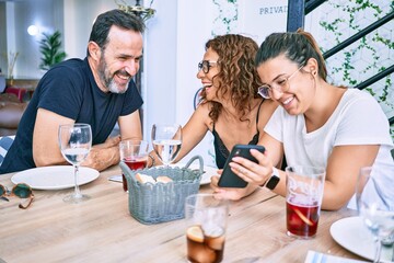 Beautiful family smiling happy using smartphone at the restaurant