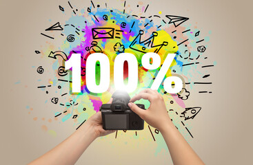 Close-up of a hand holding digital camera with abstract drawing and 100% inscription