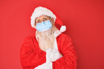 Old senior man wearing santa claus costume wearing safety mask happy face smiling with crossed arms looking at the camera. positive person.