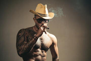 Sexy man face. Imposing guy in glasses smoking cigar. Mens beauty, fashion portrait.