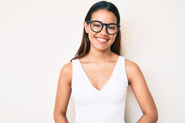 Young beautiful latin girl wearing casual clothes and glasses with a happy and cool smile on face....