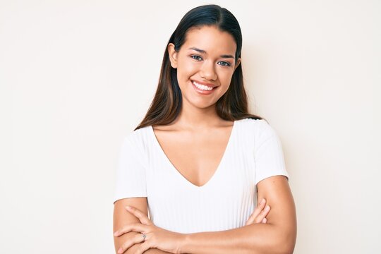 Young beautiful latin girl wearing casual white tshirt happy face smiling with crossed arms looking at the camera. positive person.