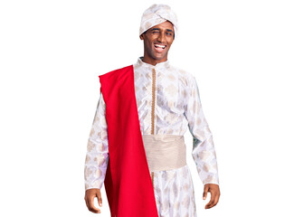 African handsome man wearing tradition sherwani saree clothes winking looking at the camera with...