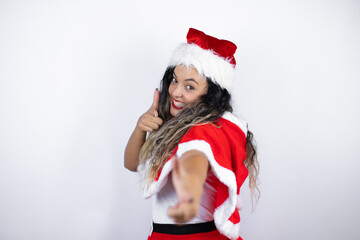 Young beautiful woman wearing a Santa Claus costume over white background pointing to you and the camera with fingers, smiling positive and cheerful