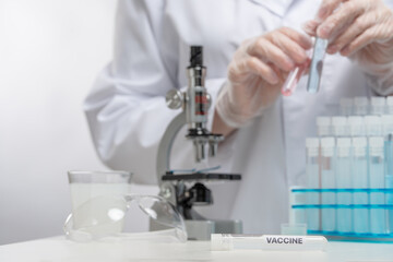 Fototapeta premium Microbiologist in protective gloves takes biological tube on microscope background. Examines of coronavirus in laboratory. Healthcare and medical concept.